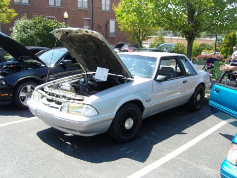 2007 Ford Mustang - Silver Ford Mustang coupe parked at an outdoor car show, hood up to display the engine.
