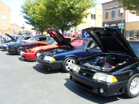 2007 Ford Mustang - Several Ford Mustangs are parked in a row with their hoods open, displaying their engines.