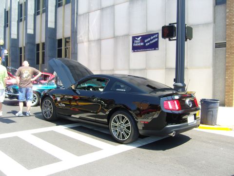 2007 Ford Mustang - A black Ford Mustang is parked on a street with its hood open, alongside other vehicles.