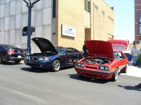2007 Ford Mustang - A red 1985 Ford Mustang is parked with its hood open, alongside other vehicles.