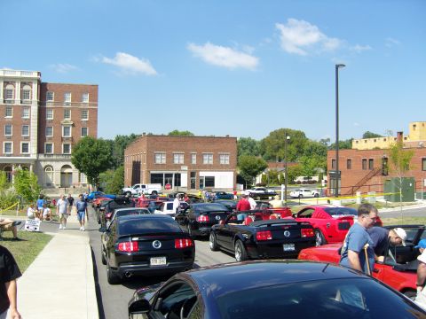 2007 Ford Mustang - A street lined with Ford Mustangs, likely from the S197 generation, at a car show event.