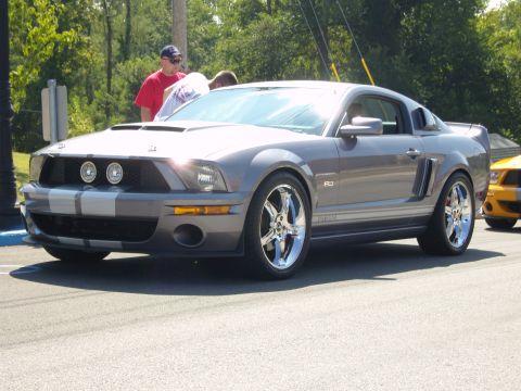 2007 Ford Mustang - A gray Ford Mustang GT500 is parked on the street, with another Mustang visible in the background.