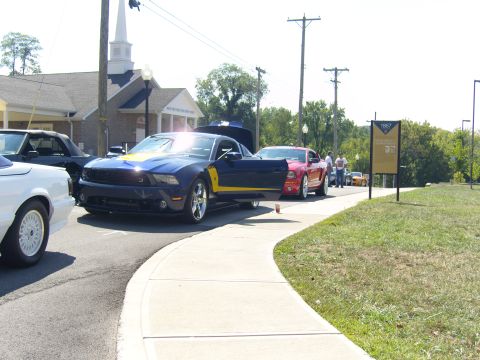 2007 Ford Mustang - Several Ford Mustangs are parked in a line on a sunny day, with a church in the background.