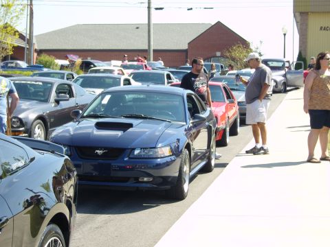 2007 Ford Mustang - A line of Ford Mustangs are parked on a street during a car show.