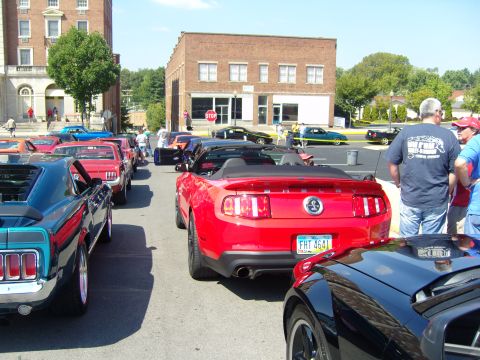 2007 Ford Mustang - A line of cars, including a red 2007 Ford Mustang convertible, parked on a street.