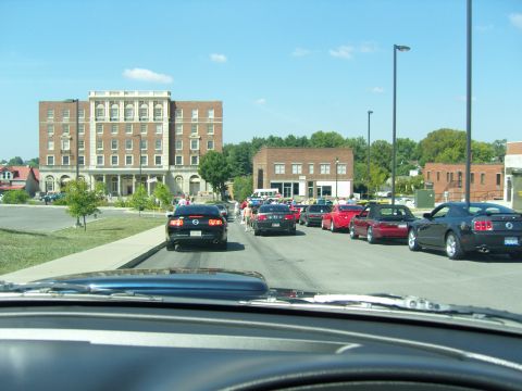 2007 Ford Mustang - A line of Ford Mustangs, including a black 2007 model, are seen from the driver's perspective during a car show event.