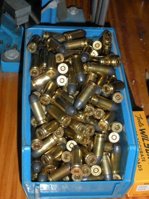 1996 Ford Bronco - A blue bin filled with bullets and cartridges, beside a box of Wilson Combat ammunition.