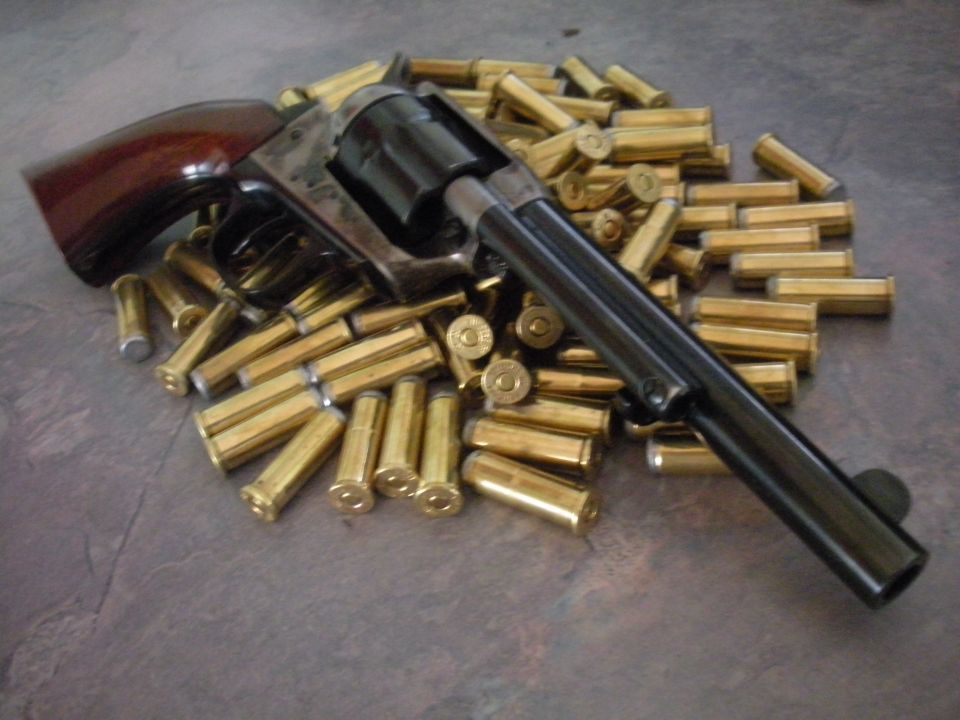 Revolver with wooden grip rests on a pile of brass cartridges