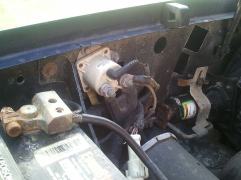 1994 Ford Bronco - Close-up view of electrical components in a vehicle's engine bay, a starter solenoid and battery terminal.