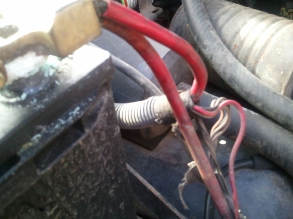 close-up of car battery terminals and red wires connected to them