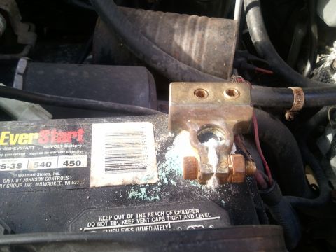 1994 Ford Bronco - Close-up of a car battery's corroded terminals and a black EverStart battery.