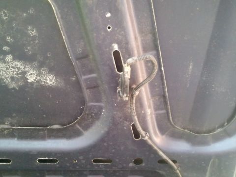 1994 Ford Bronco - The underside of a car hood shows a wire harness and some discoloration.
