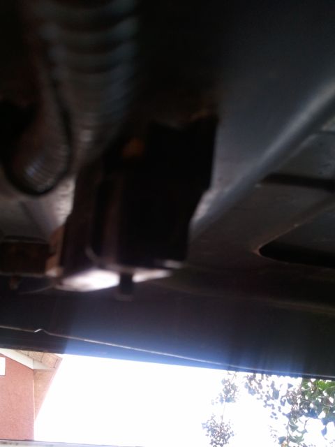 1994 Ford Bronco - The underside of a vehicle is visible, with a bright sky and some foliage in the background.
