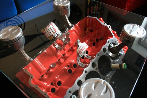 1973 Ford Ranchero - Engine block and pistons form a unique table display with various automotive and beverage memorabilia.