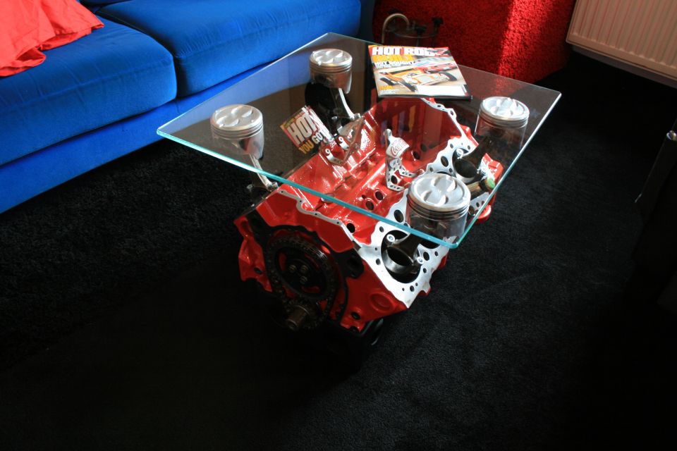 Engine block and pistons used as a coffee table with a 'Hot Rod' magazine on top