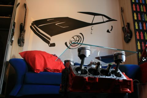 1973 Ford Ranchero - This room features a unique coffee table made from an engine block, alongside a car graphic on the wall.