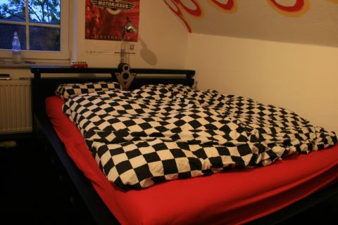1973 Ford Ranchero - A bed with a checkered comforter and red sheets is shown in a room with posters on the wall.