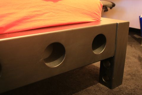 1973 Ford Ranchero - A detail shot of a bed frame with a textured orange blanket draped over it.