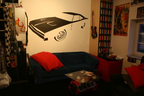 1973 Ford Ranchero - A room decorated with a large car decal on the wall, a sofa, and various automotive-themed items.