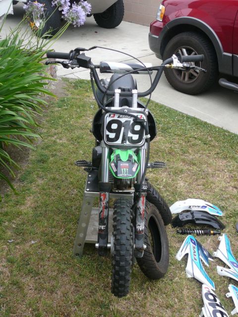 1988 Ford Bronco - Mini dirt bike with number 919 on front plate and Monster Energy sticker. Parts are scattered around it.