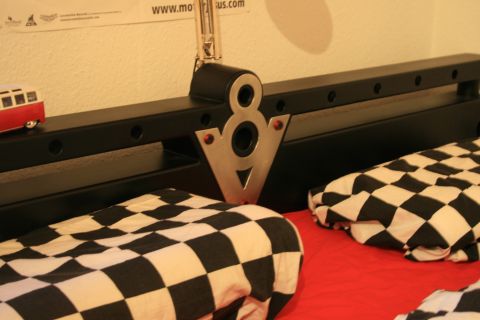 1973 Ford Ranchero - A V8 emblem is mounted above checkered blankets, with a small red and white toy vehicle visible on the left.