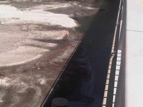1986 Ford Bronco - Construction site with red string lines marking out an area, wet ground, and a concrete barrier.