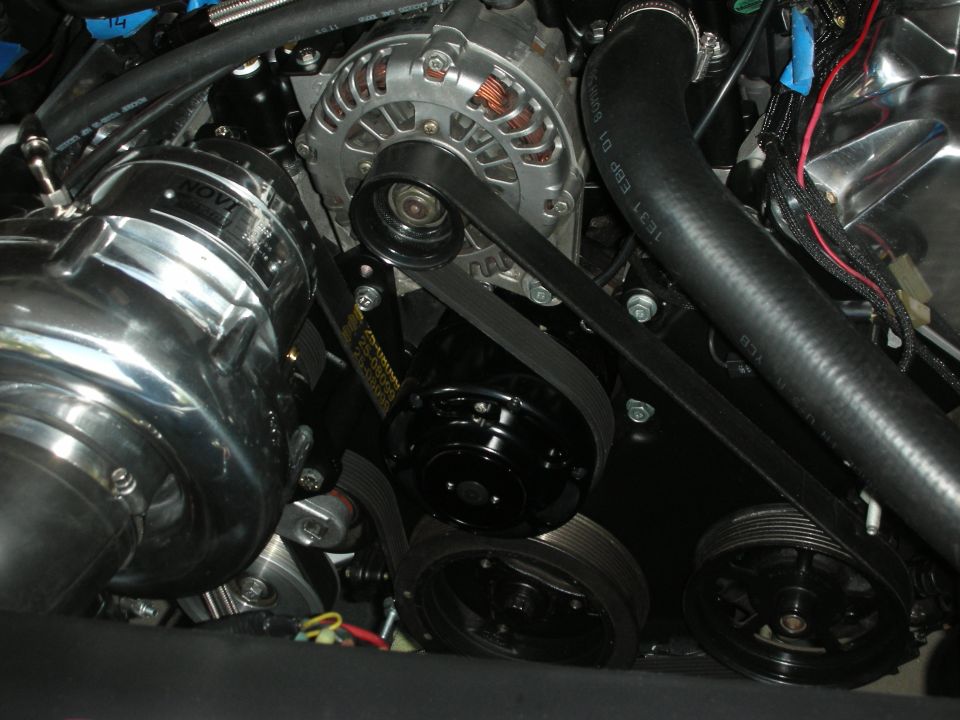 Close-up of a polished supercharger, alternator, and serpentine belt system in an engine bay