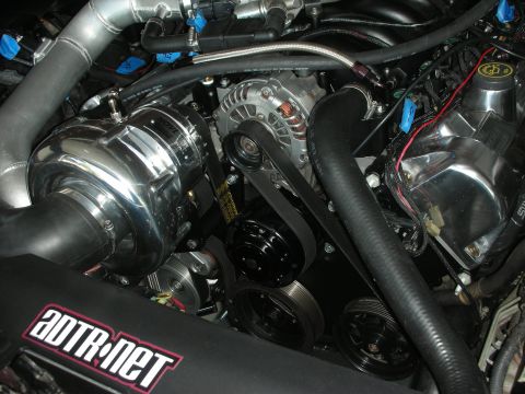 1992 Ford Crown Victoria - Close-up of a supercharged engine bay a polished supercharger and a black air intake tube with a prominent logo.