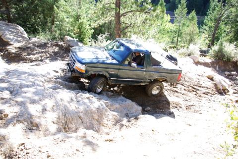 1995 Ford Bronco - Ford Bronco tackling a challenging off-road course with steep inclines and large rocks.