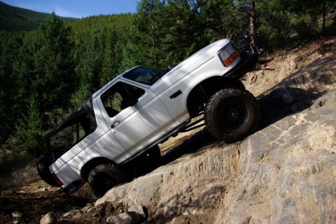 1995 Ford Bronco - This 1995 Ford Bronco navigates a challenging rocky trail in a wooded area.