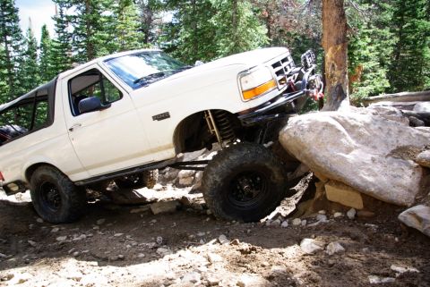 1995 Ford Bronco - 1995 Ford Bronco tackling a challenging off-road obstacle course with large boulders.