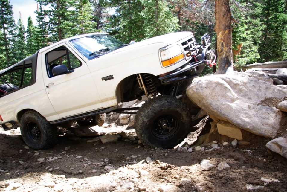 White 1995 Ford Bronco navigating large rocks on a dirt trail