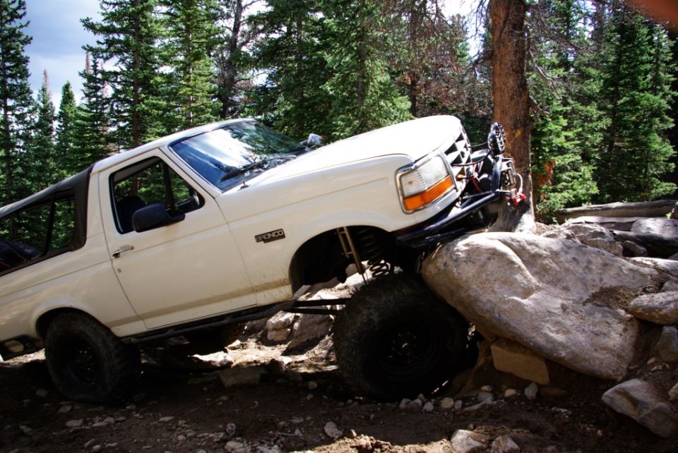 White 1995 Ford Bronco navigating large rocks on a trail
