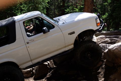 1995 Ford Bronco - White 1995 Ford Bronco tackling a challenging off-road trail with large rocks.