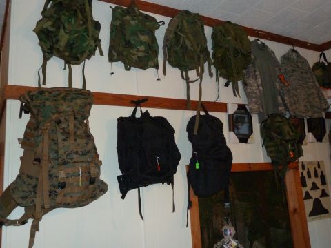 1992 Ford Mustang - A collection of military-style backpacks and tactical clothing are displayed on a wall.