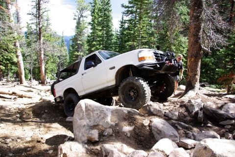 1995 Ford Bronco - This 1995 Ford Bronco tackles a challenging rocky trail surrounded by pine trees.