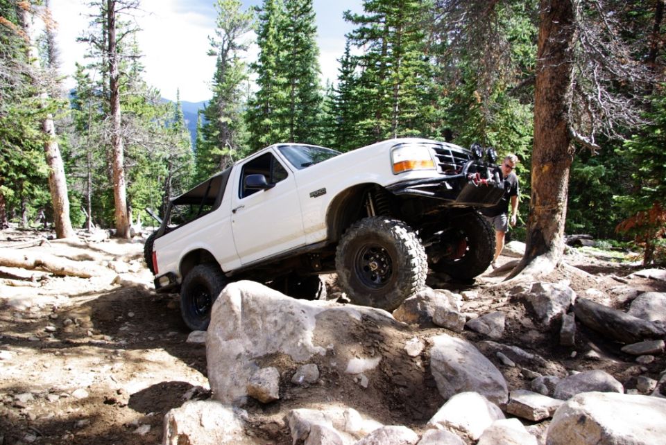 White 1995 Ford Bronco navigating a rocky off-road trail