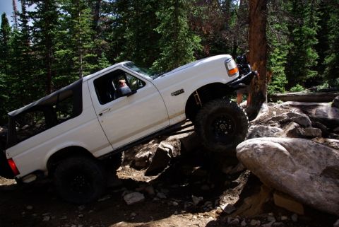 1995 Ford Bronco - 1995 Ford Bronco tackling a challenging off-road course on a sunny day.