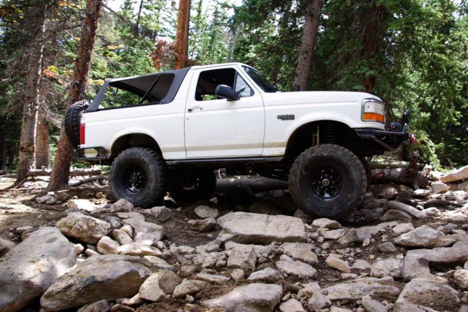 White Ford Bronco with lifted suspension and large tires navigating a rocky trail