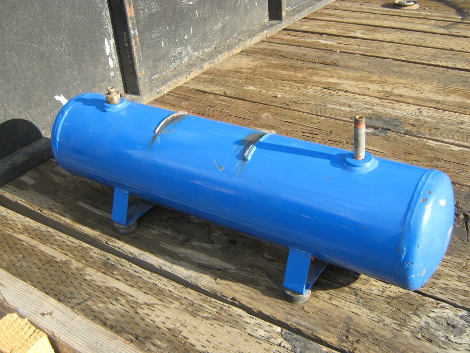 Blue air tank with brass fittings on wooden planks