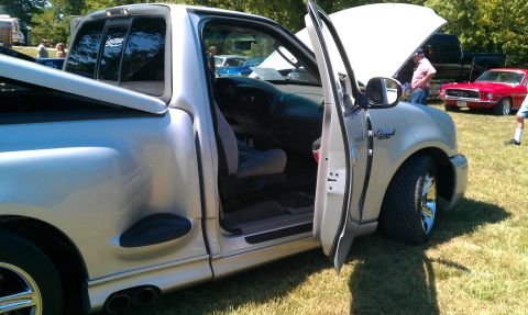 2002 Ford F-150 - A silver pickup truck is parked on grass with its hood and driver's door open, alongside other vehicles.