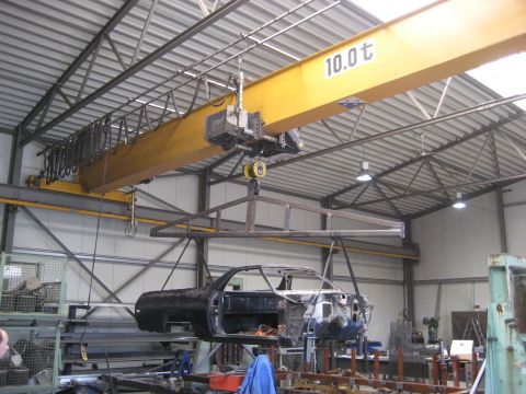 1973 Ford Ranchero - A car body is being lifted by a 10-ton crane inside a large industrial building.