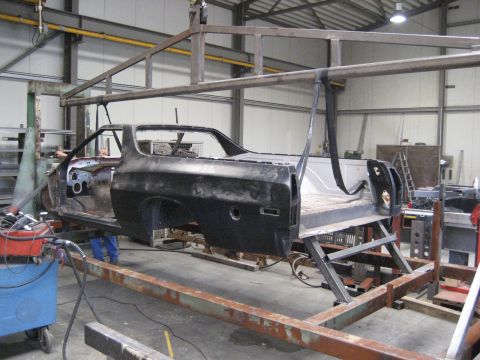 1973 Ford Ranchero - The body of a 1973 Ford Ranchero is suspended on a metal frame in a workshop, indicating a restoration project.