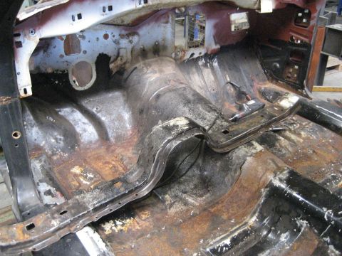 1973 Ford Ranchero - The interior floor pan of a vehicle shows significant rust and damage, indicating a need for extensive restoration.