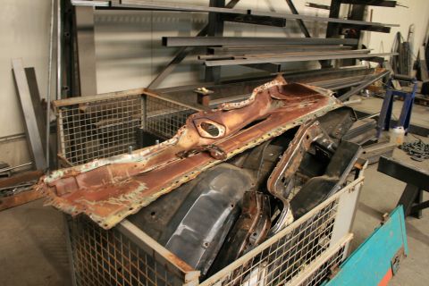 1973 Ford Ranchero - Various heavily rusted car body parts are stored in a wire basket in a workshop.