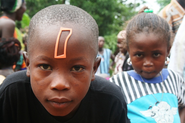 Two children, one with an orange marking on forehead, the other wearing large earrings