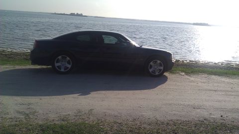 2006 Dodge Charger - A dark 2006 Dodge Charger is parked on a dirt road next to a body of water.