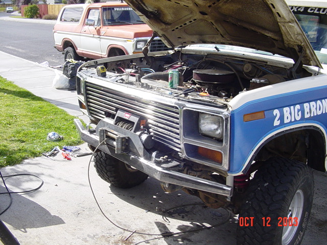 Blue '2 Big Bronco' with hood up and winch mounted, orange Bronco in background, driveway build, Oct 2003