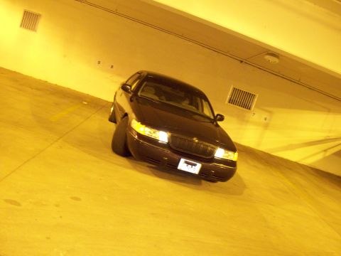 1999 Mercury Grand Marquis - A dark 1999 Mercury Grand Marquis is parked in a dimly lit garage.