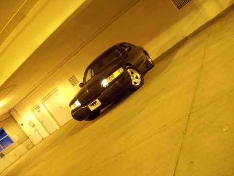 1999 Mercury Grand Marquis - Sedan with a distinctive grille and chrome wheels parked indoors under yellow lighting.